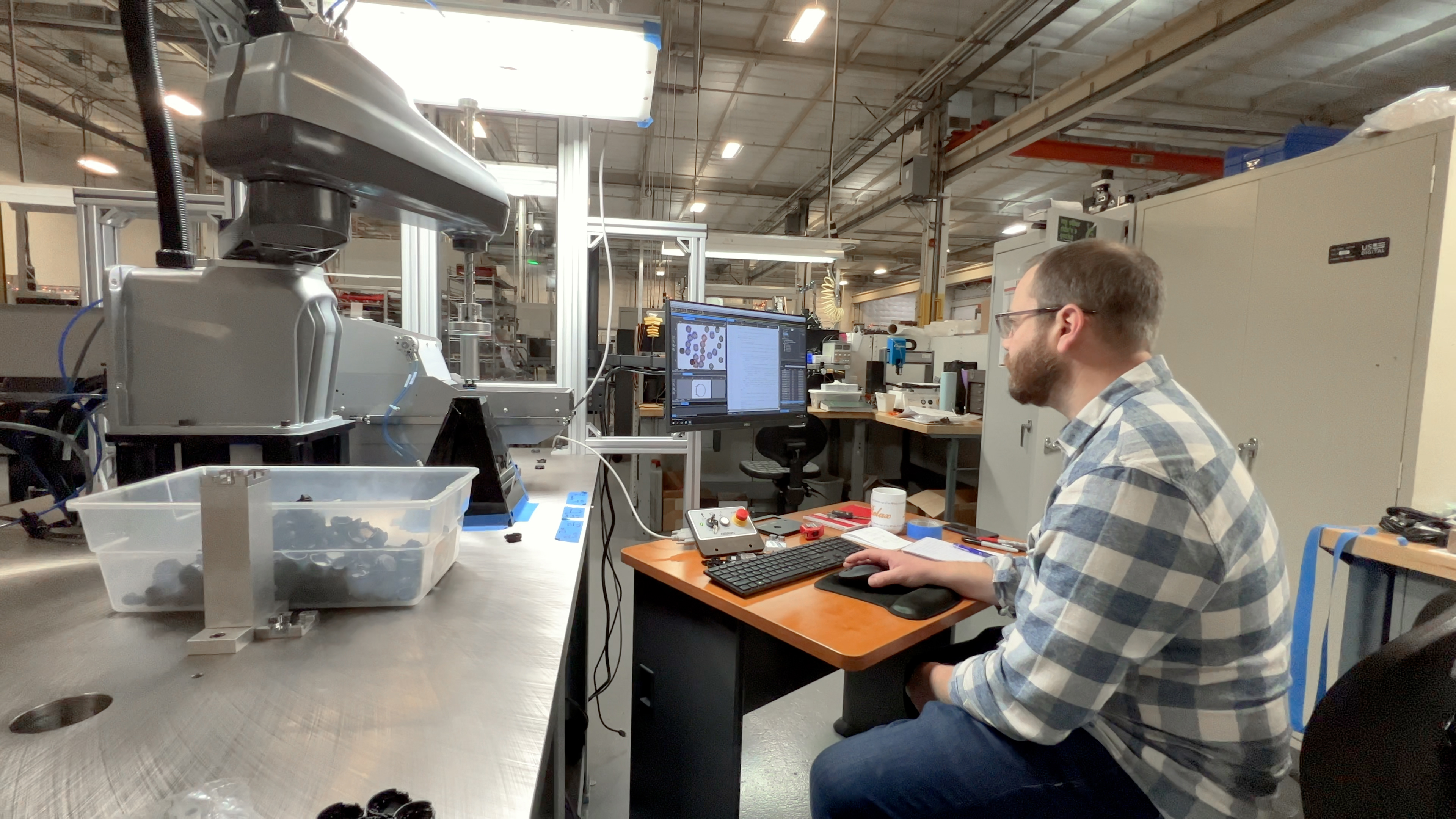 engineer working on a computer near a partially built machine in an industrial area